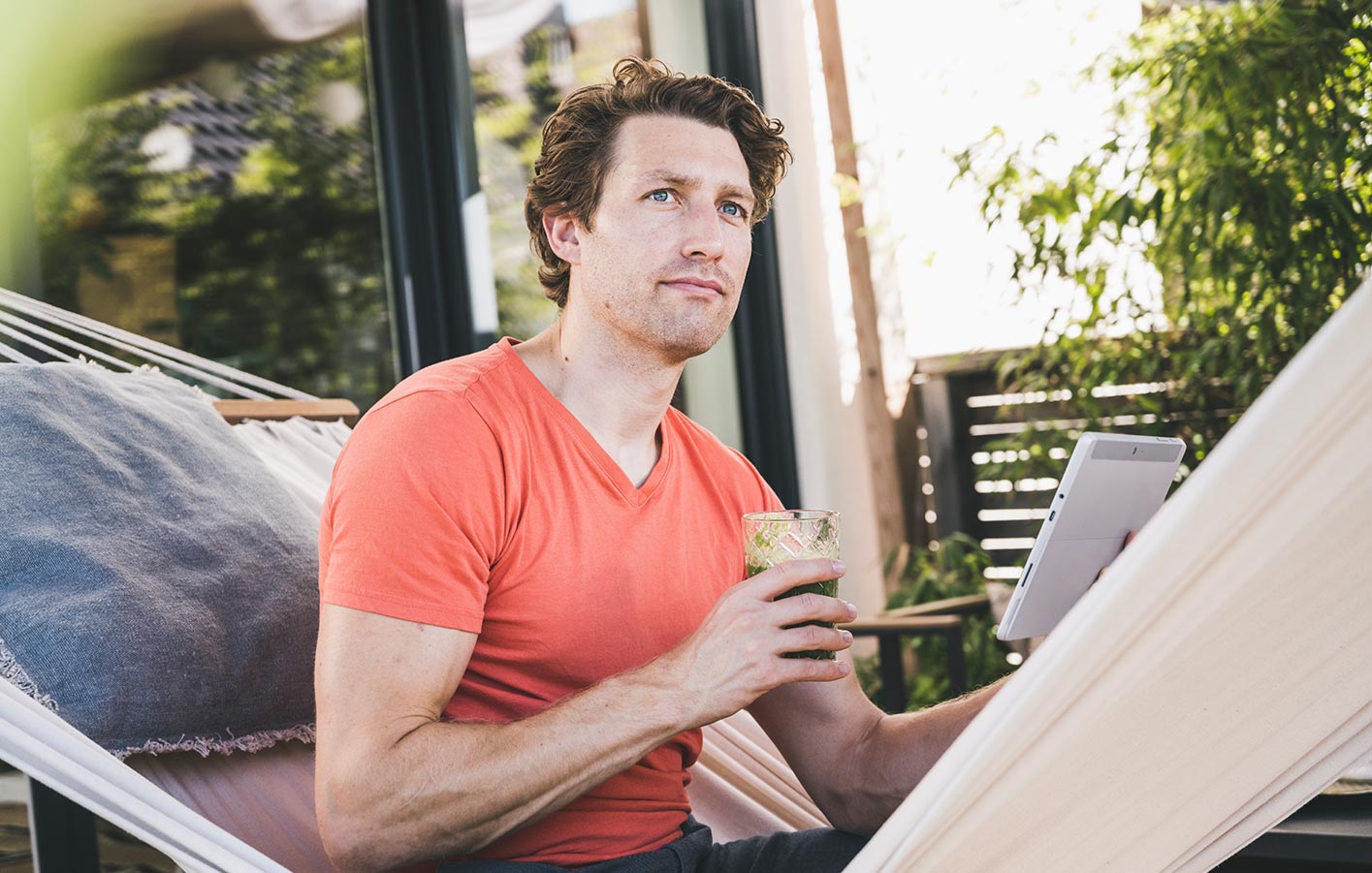 Planung der Terrassenüberdachung – Schritt für Schritt Mann in Hängematte plant Terrassenüberdachung und genießt einen Drink.